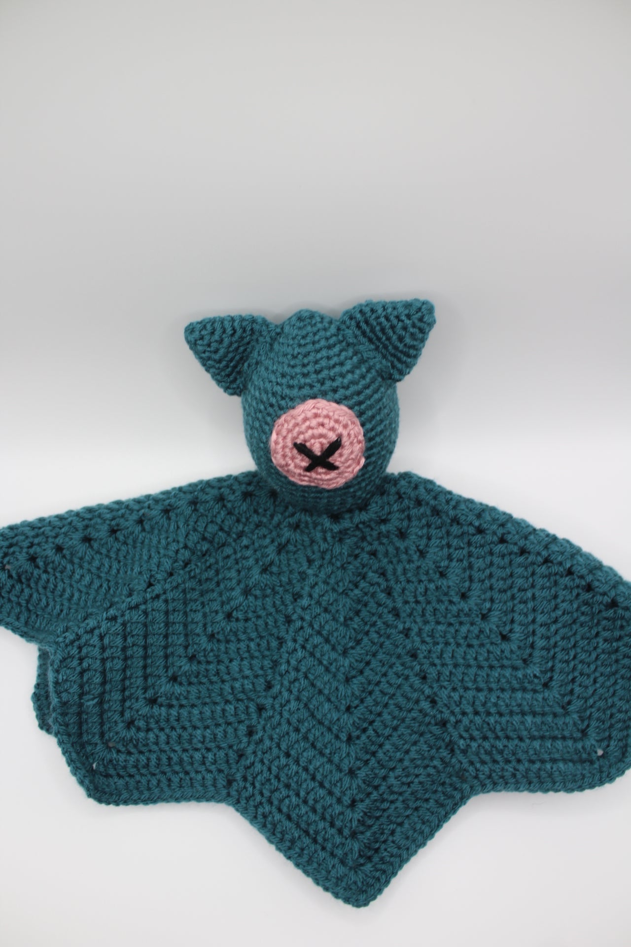 Teal crocheted item with a pink center on a white background