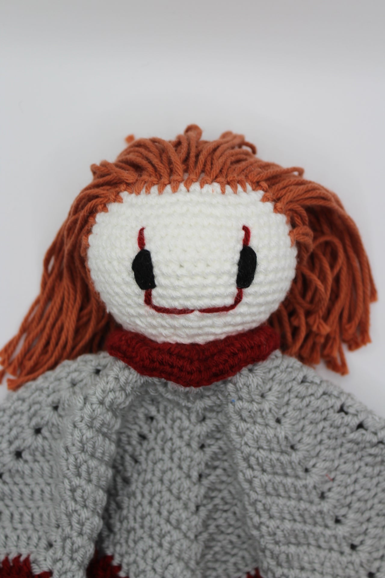 Crocheted baby clown lovey on a white background