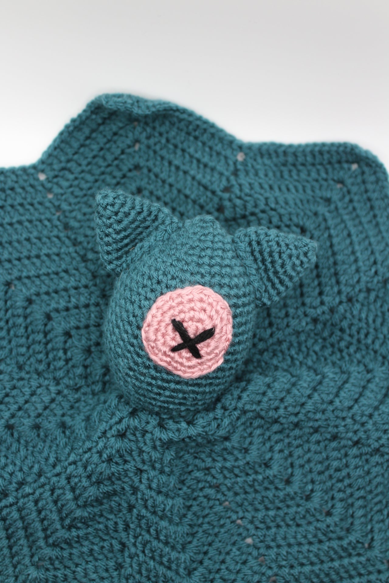Teal crochet item with pink button eye and cat ears