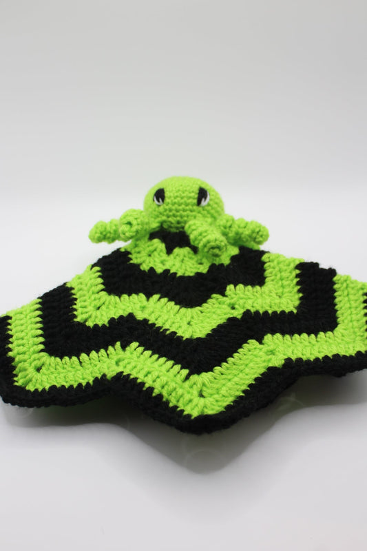 Crocheted spider baby blanket with black and green pattern on a white background