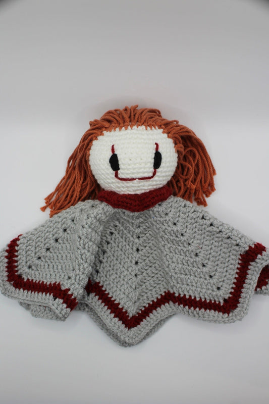 Crocheted clown baby lovey with orange hair and a white face on a white background